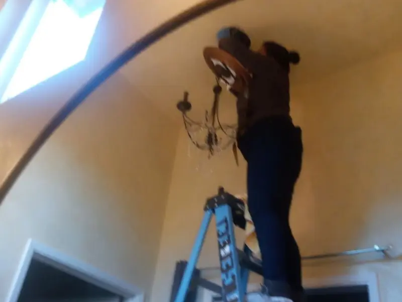 Electrician installing a chandelier in a Thurmont residence